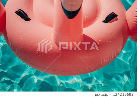 A pink inflatable flamingo is floating in a pool. The water is clear and calm. The flamingo is the main focus of the image, and it is enjoying its time in the water. A pink inflatable flamingo is floating in a pool. The water is clear and calm. The flamingo is the main focus of the image, and it is enjoying its time in the water. 124219692