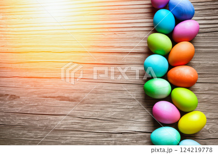 Top-Down View Of Aged Wooden Surface With Festive Easter Eggs Closeup Shot Capturing Orange Light Glare And Vertical Array On Rustic Wood Grain, Infusing Celebratory Vibe 124219778