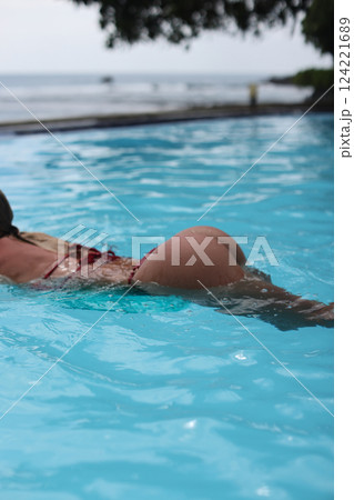 A woman enjoying swimming in a beautifully clear pool located by the vast ocean shores A woman enjoying swimming in a beautifully clear pool located by the vast ocean shores 124221689
