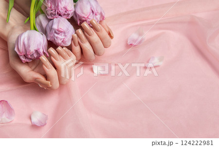 Woman hands holding pink tulips showing nude manicure on pink background Woman hands holding pink tulips showing nude manicure on pink background 124222981