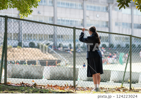 フェンス越しに学校を見る女子生徒 フェンス越しに学校を見る女子生徒 124223024