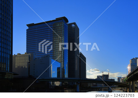 堂島川にかかる高速道路と川沿いの高層ビルのガラス窓に朝日が輝くビジネス街 堂島川にかかる高速道路と川沿いの高層ビルのガラス窓に朝日が輝くビジネス街 124223703