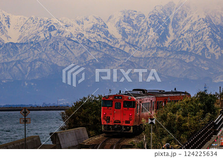 美しい立山連峰を背景に走る氷見線の列車の絶景 124225634
