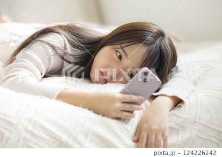 ベッドでスマホを見る女性 124226242