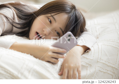 ベッドでスマホを見る女性 124226243