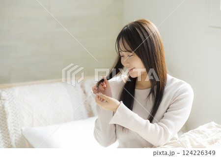ベッドでヘアケアの効果を実感する女性　 124226349