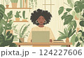 Woman with curly hair working on a laptop surrounded by houseplants in cozy home office 124227606