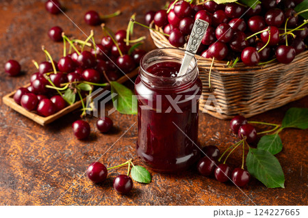 Cherry jam and fresh berries with leaves on an old brown table. 124227665