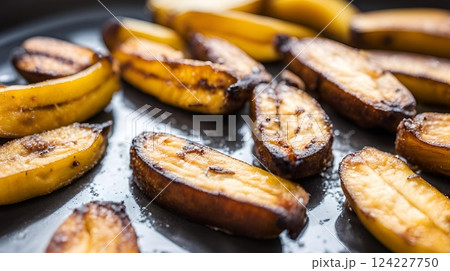 Freshly baked hot fried plantain bananas with a crispy golden exterior and a sweet tender interior. A delightful treat straight from the oven, offering a warm tropical flavor. AI Generated 124227750