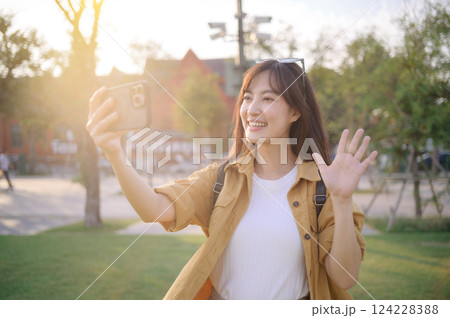 Traveler asian woman in her 30s making a livestream or selfie with a smartphone in evening scene while solo travel in Bangkok, Thailand. Traveler asian woman in her 30s making a livestream or selfie with a smartphone in evening scene while solo travel in Bangkok, Thailand. 124228388