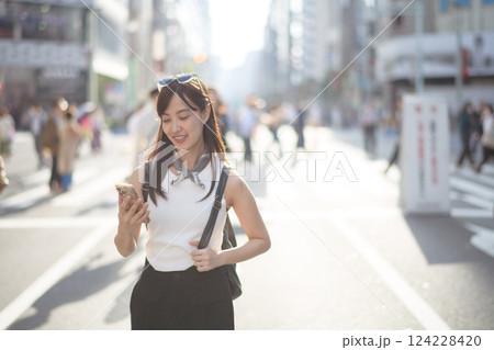 Tokyo smiles, A joyful woman in Tokyo, using her smartphone amidst the bustling urban environment. Tokyo smiles, A joyful woman in Tokyo, using her smartphone amidst the bustling urban environment. 124228420