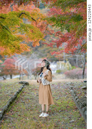 Asian woman in casual dress embraces the fall beauty of Japan, enjoying a holiday filled with smiles, fashion, and vibrant foliage. A cheerful portrait capturing the essence of a vacation. Asian woman in casual dress embraces the fall beauty of Japan, enjoying a holiday filled with smiles, fashion, and vibrant foliage. A cheerful portrait capturing the essence of a vacation. 124228443