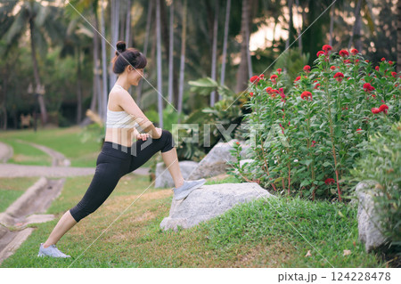 Sportswoman. Fit young Asian woman with sportswear stretching muscle in park before running and enjoying healthy outdoor. Fitness runner girl in public park. Wellness being concept 124228478