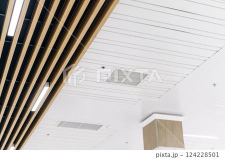 Ceiling mounted cassette type air conditioner and modern lamp light on a white ceiling. duct air conditioner for office or home 124228501
