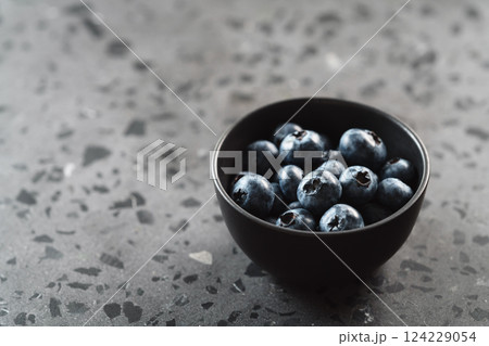 Ripe blueberries in black bowl on concrete background with copy space 124229054