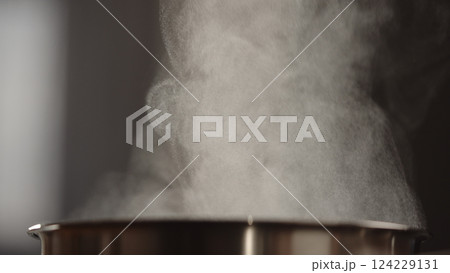closeup shot of steam rising from steel saucepan on stove 124229131