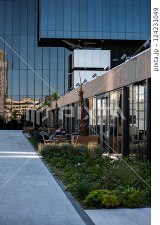 modern architecture with glass facade and outdoor terrace with cafes in vibrant urban setting during bright daylight, skyscraper of Cuatro Torres area, Madrid modern architecture with glass facade and outdoor terrace with cafes in vibrant urban setting during bright daylight, skyscraper of Cuatro Torres area, Madrid 124231049