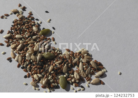 A mix of different seeds on a white background. Sunflower seeds, black and white sesame seeds, flax and pumpkin seeds - all together. Healthy food. A mix of different seeds on a white background. Sunflower seeds, black and white sesame seeds, flax and pumpkin seeds - all together. Healthy food. 124232753