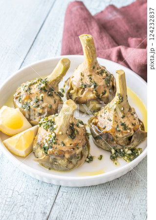 Four Roman-style artichokes served on white plate, tender and beautifully seasoned Four Roman-style artichokes served on white plate, tender and beautifully seasoned 124232837