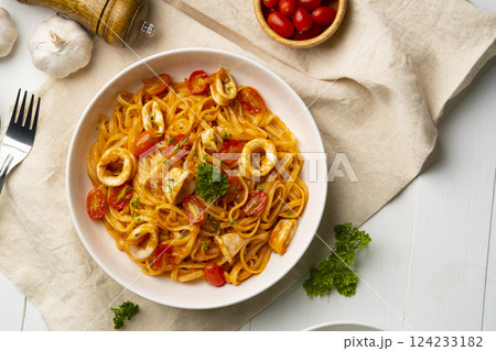 Linguine pasta with squid and cherry tomato in tomato sauce in white plate.Top view 124233182