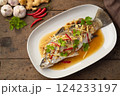 Steamed Seabass fish with Soybean Paste sauce in white plate.Top view 124233197