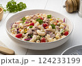 Homemade macaroni salad with elbow pasta and canned tuna, carrot, Purple cabbage, corn, tomato, green peas and mayonnaise dressing in a white plate on wooden table. 124233199