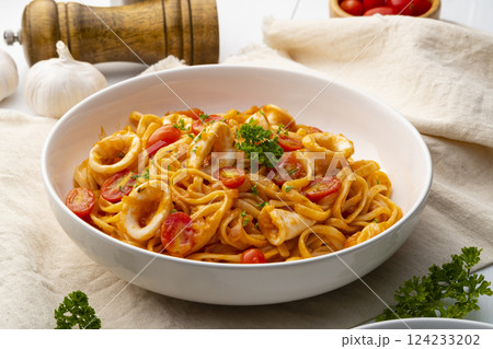Linguine pasta with squid and cherry tomato in tomato sauce in white plate 124233202