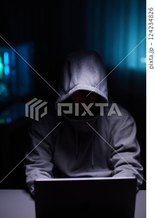 Hacker using the computer. Man in a hoodie breaks the access to steal information and infects computers and systems Hacker using the computer. Man in a hoodie breaks the access to steal information and infects computers and systems 124234826