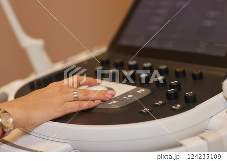 Sonography. Medical ultrasound transducer in doctor's hand, close-up near ultrasound machine in medical clinic 124235109