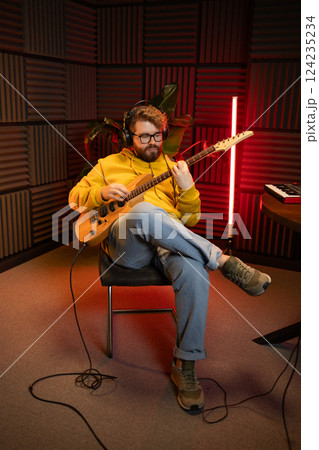 Bearded man playing electric guitar at music studio. Performance and show in the music business, streaming and recording music. Bearded man playing electric guitar at music studio. Performance and show in the music business, streaming and recording music. 124235234