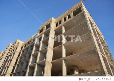 It is view of a new incomplete house without tiles on roof in sunny summer day. It is a close up view of modern house without roof. It is close up view of unfinished building apartment 124235501