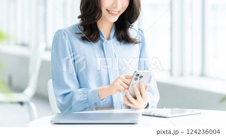 スマートフォンを使う笑顔の女性・ビジネスウーマン スマートフォンを使う笑顔の女性・ビジネスウーマン 124236004
