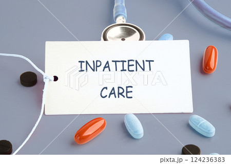 A tag labeled inpatient care rests on a gray surface surrounded by different types of medical pills and a stethoscope A tag labeled inpatient care rests on a gray surface surrounded by different types of medical pills and a stethoscope 124236383