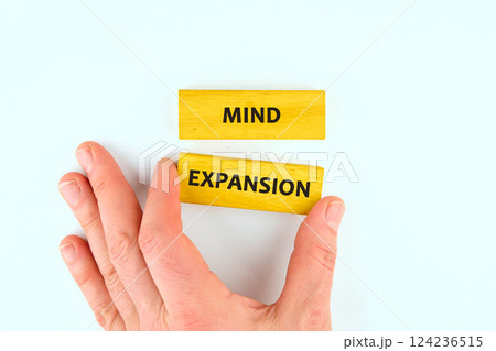 A hand reaches for wooden blocks labeled with the words mind and expansion, symbolizing the growth of knowledge in business finance education A hand reaches for wooden blocks labeled with the words mind and expansion, symbolizing the growth of knowledge in business finance education 124236515