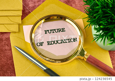 Close-up view of a magnifying glass revealing the future of education text among a workspace featuring stationery and a plant 124236545