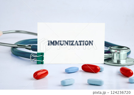 Medical tools and capsules frame a card marked immunization, emphasizing vaccination's role in health 124236720