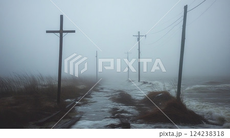 Misty coastal scene with broken wooden poles and a damaged power line standing in rough ocean waves. Misty coastal scene with broken wooden poles and a damaged power line standing in rough ocean waves. 124238318