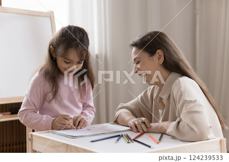 Young mom laughing looking at small girl drawing funny sketch 124239533