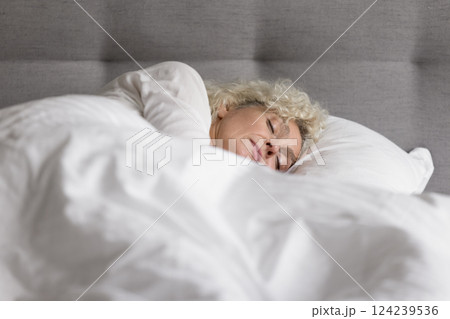 Beautiful serene old woman sleeping deeply in large cozy bed 124239536