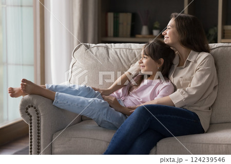 Affectionate mother sitting on sofa holding little daughter in arms Affectionate mother sitting on sofa holding little daughter in arms 124239546