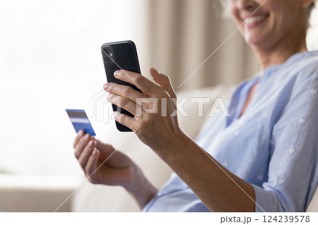 Smiling aged female holding smartphone credit bank card in hands 124239578