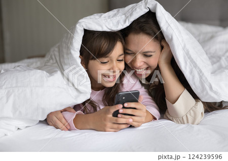 Young mommy little daughter lying on bed using mobile phone 124239596