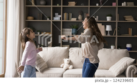 Active young mom little girl jumping dancing in living room 124239605