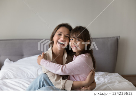 Portrait laughing young mom holding little daughter on knees Portrait laughing young mom holding little daughter on knees 124239612
