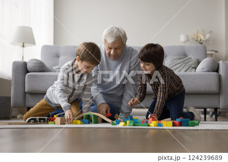 Old grandfather two grandsons enjoy playing with toys on floor Old grandfather two grandsons enjoy playing with toys on floor 124239689