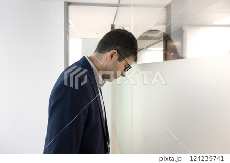 Businessman feeling emotional exhaustion leans head against wall 124239741