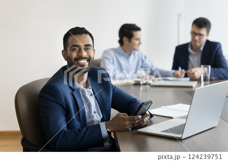 Portrait of happy Indian businessman holding smartphone, looking at camera 124239751