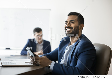 Smiling Indian businessman getting happy by received news in sms Smiling Indian businessman getting happy by received news in sms 124239762