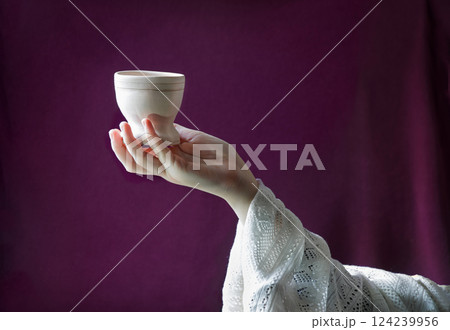 A hand in ancient clothing holds a clay bowl 124239956