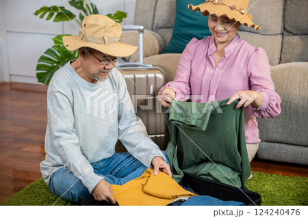 Asian couple old senior marry retired couple smiling prepare luggage suitcase arranging for travel, Romantic mature retired packing clothes travel bag suitcase together on floor at home for holiday 124240476